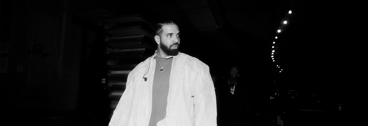 Es ist der Rapper Kurdo zu sehen, der auf einer Dachterasse steht, während im Hintergrund die Sonne untergeht.